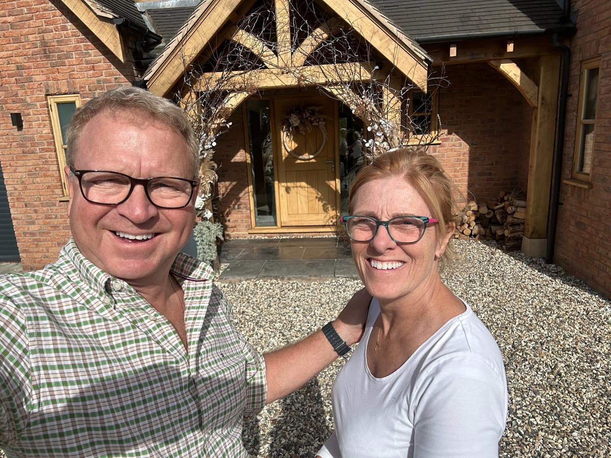 Darren and Claire smiling in front of their decorated timber porch.